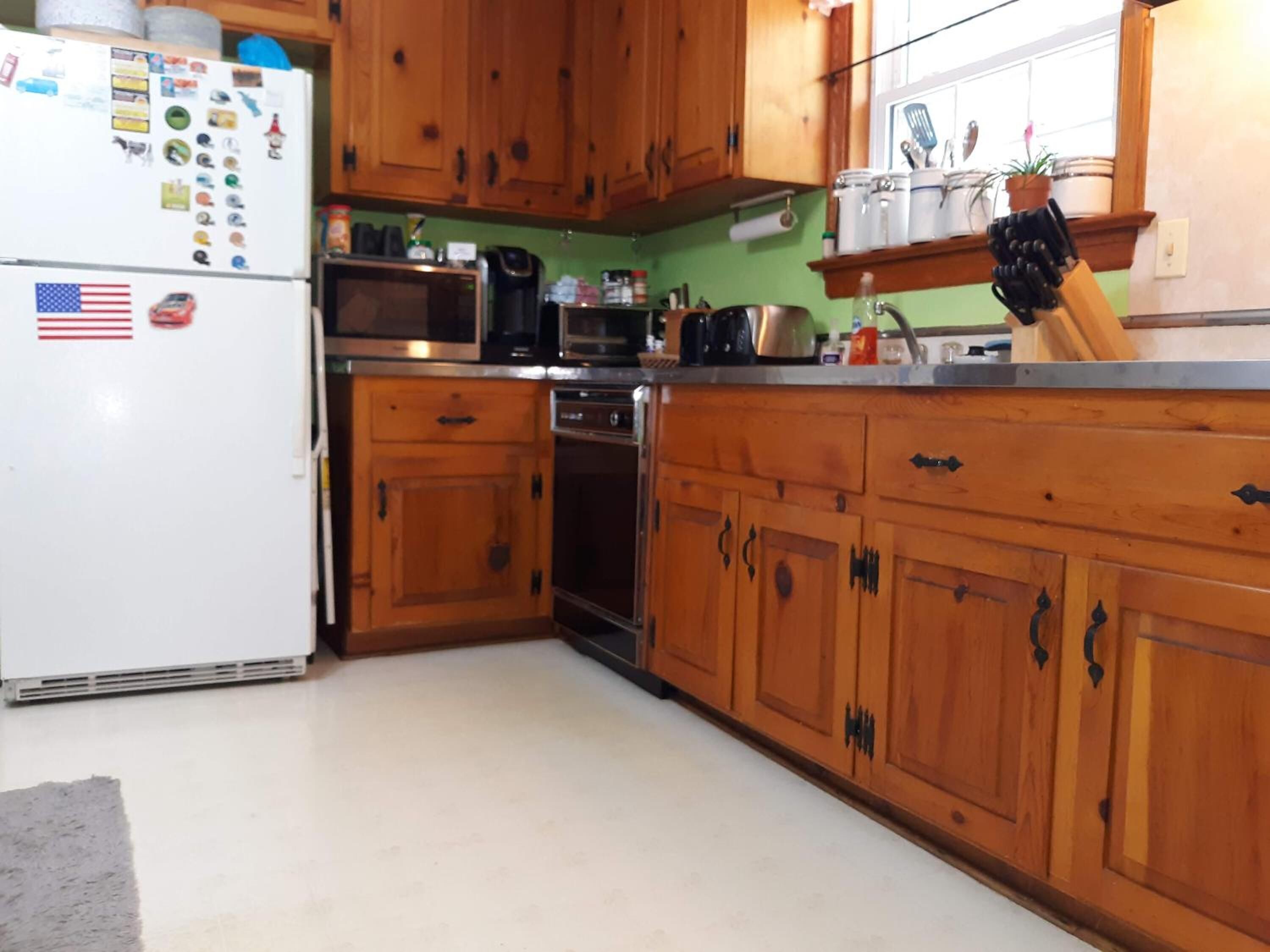 A kitchen with wooden cabinets, a white refrigerator, a microwave, an oven, and a sink.