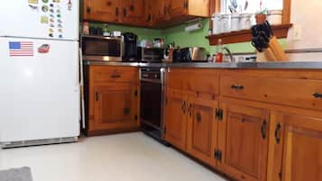 A kitchen with wooden cabinets, a white refrigerator, a microwave, an oven, and a sink.