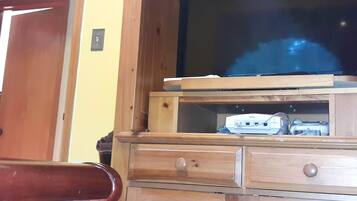 A wooden entertainment center with a television, a gaming console, and drawers.
