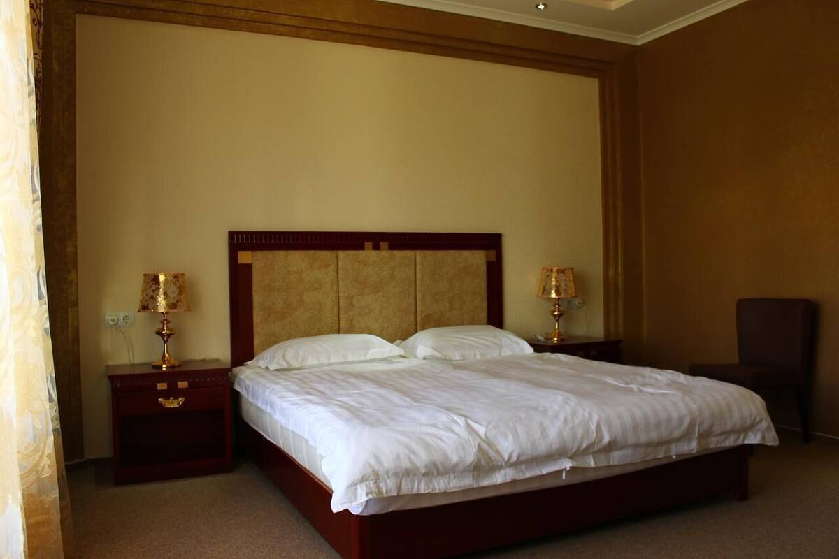 A hotel room with a large bed, two bedside tables with lamps, and a chair.