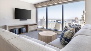 A modern living room with a large window, a flat-screen TV, a sofa, and a coffee table.