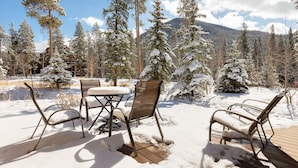 An outdoor seating area with metal chairs and a table, surrounded by snow-covered trees and a mountain in the background. - Keystone Townhome in Quiet Location Near Resort Shuttle, Access to Activities (Keystone)