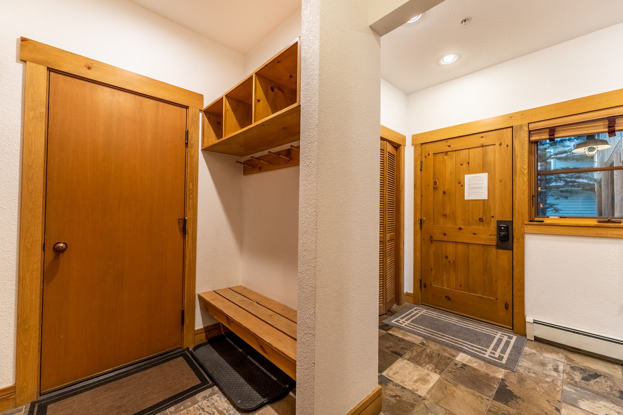 A wooden door with a bench and shelving unit in a hallway.