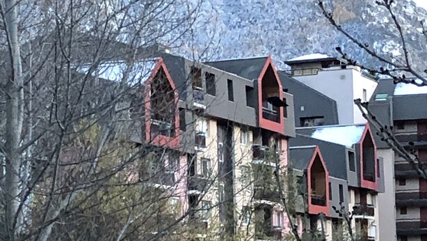 Un edificio de varios pisos con una mezcla de estilos arquitectónicos, algunos con detalles rojos en ventanas y tejados.