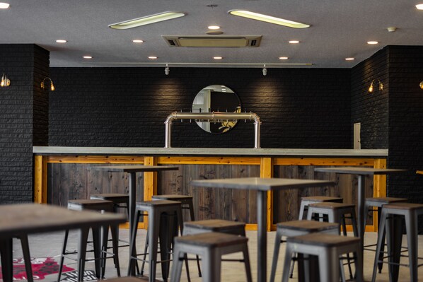 A bar area with stools, a counter, and a mirror on the wall. - The Phat Packers - Hostel (Otari)