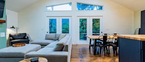 A spacious living area with a large sofa, a dining table with chairs, and a kitchen area.