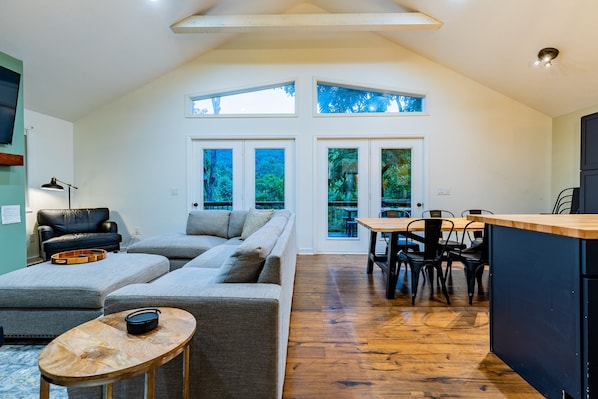 A spacious living area with a large sofa, a dining table with chairs, and a kitchen area.