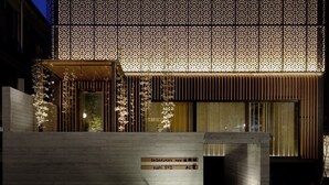Un edificio moderno con fachada de madera, un letrero que dice 'SAGAKUKAN Hotel' y 'Sushi Syo', y un diseño de pared con motivos.