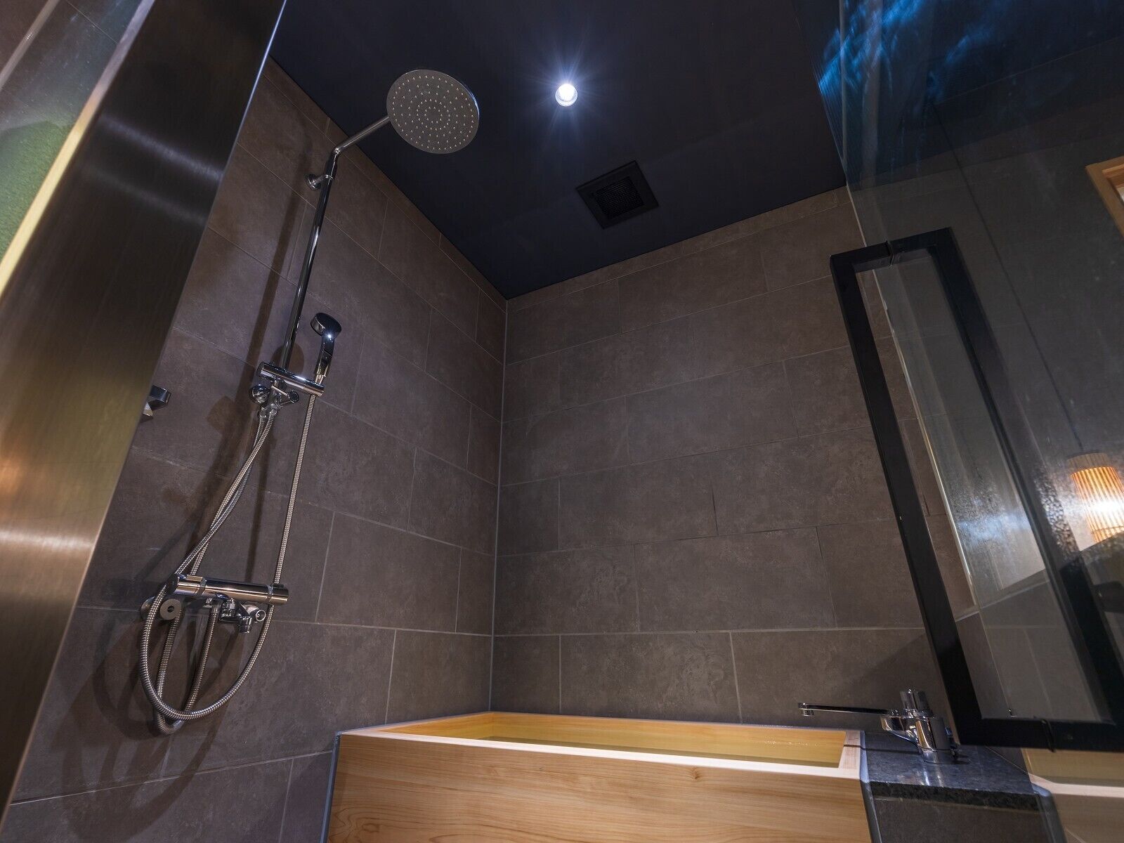 Un baño moderno con ducha, bañera de madera y un espejo grande.