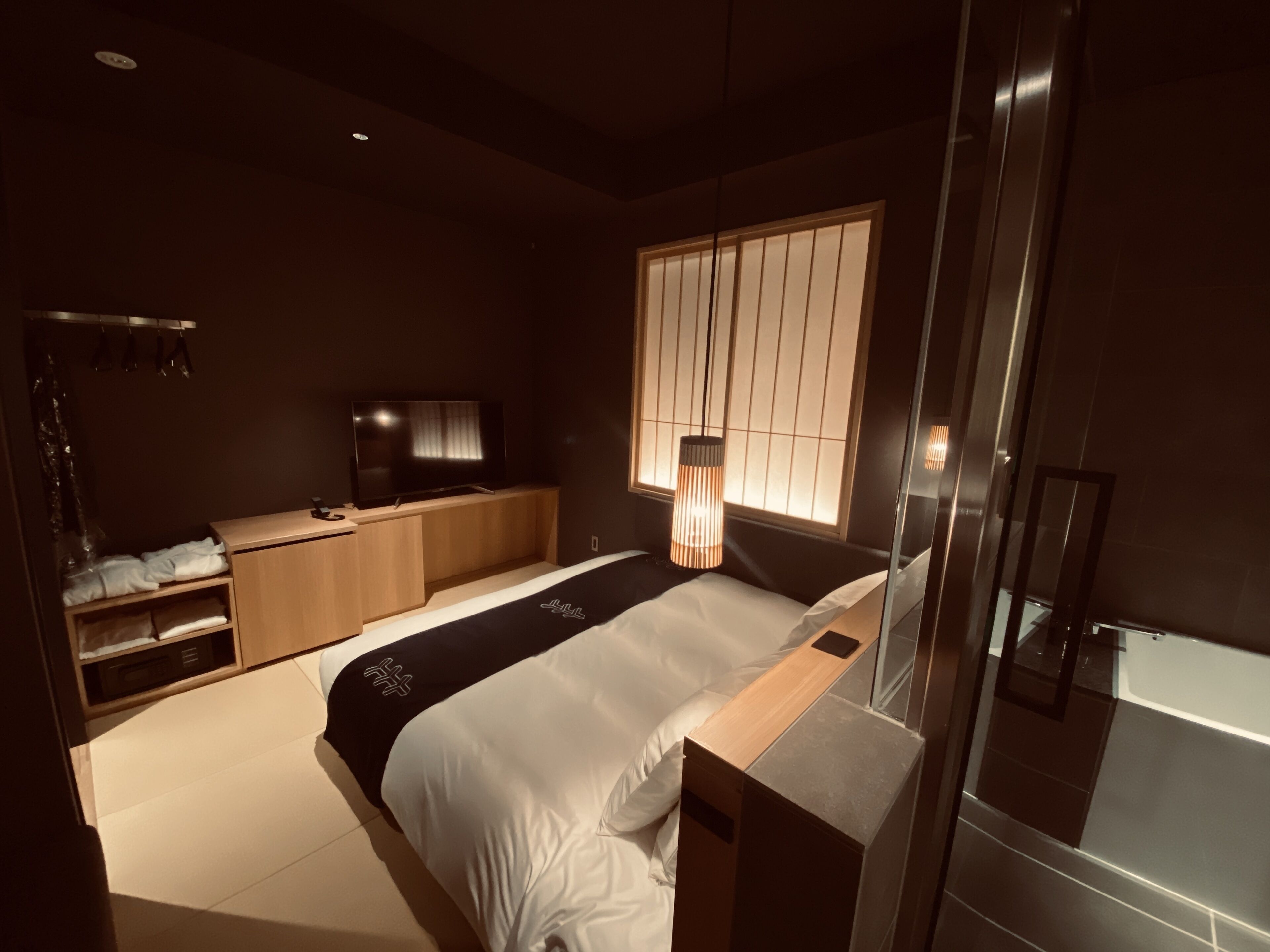 A modern bedroom with a bed, a TV, a desk, and a wardrobe.