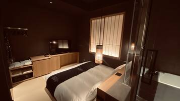 A modern bedroom with a bed, a TV, a desk, and a wardrobe.