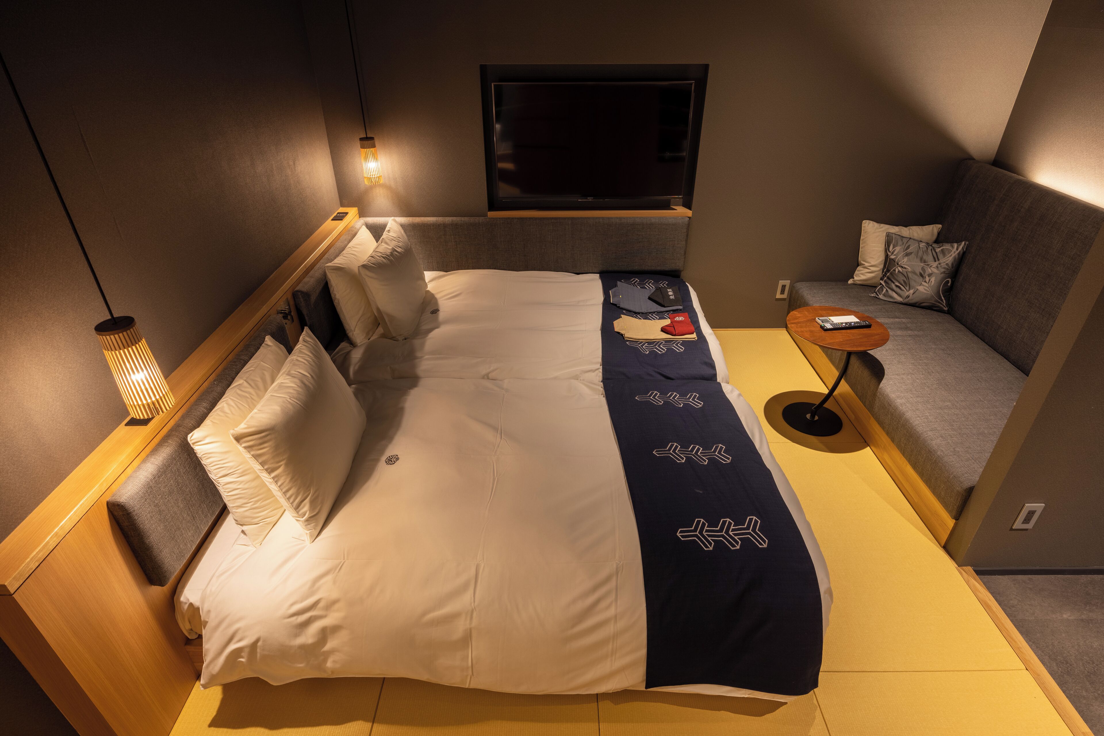 A compact hotel room with a bed, a sofa, a TV, and a small table.