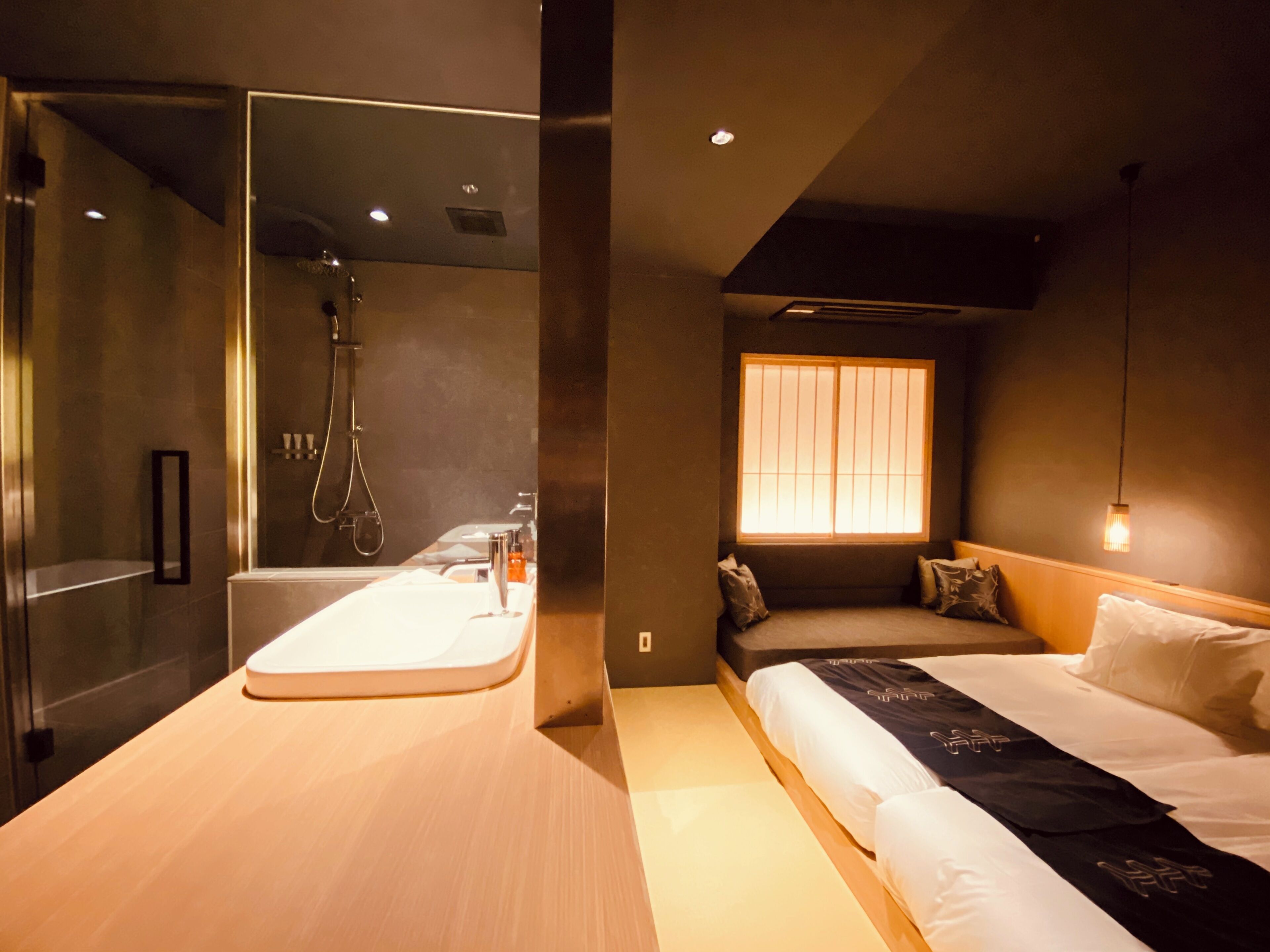 Una habitación de hotel moderna con ducha, cama, ventana y mesita de noche.