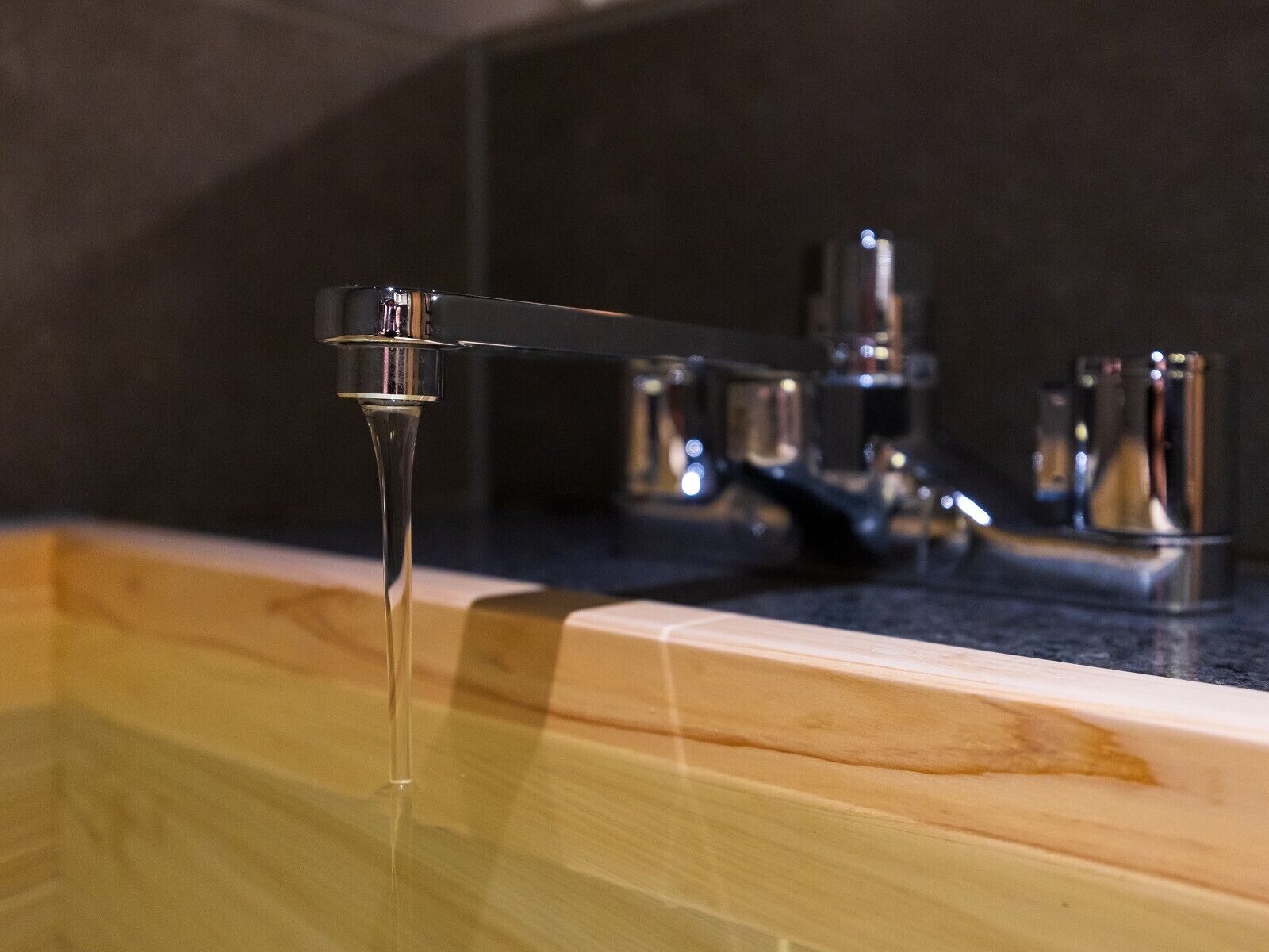 A bathroom with a wooden vanity, a modern faucet, and a mirror.