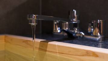 A bathroom with a wooden vanity, a modern faucet, and a mirror.