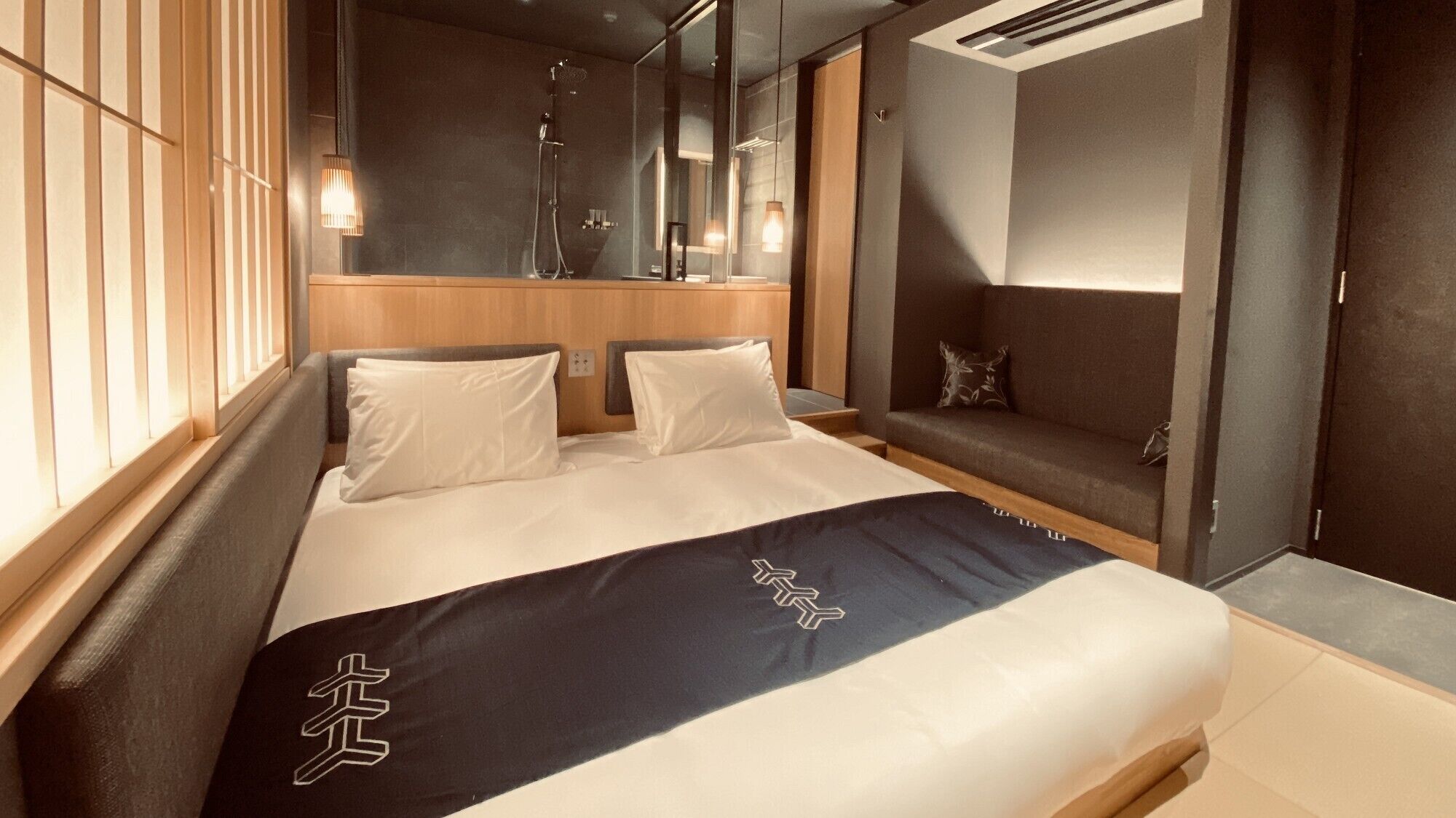 Una habitación de hotel moderna con una cama grande, una zona de estar y una ducha.