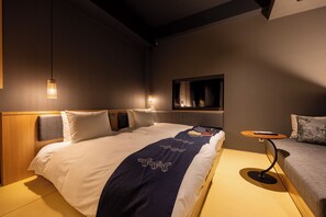 Habitación de hotel moderna con una cama bien hecha, una mesita redonda pequeña y un sofá.