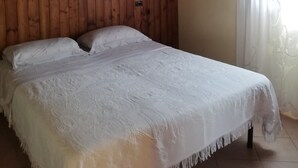Ein Zimmer mit Holzwänden, einem Bett, einer Lampe und einem Fenster mit Vorhängen.