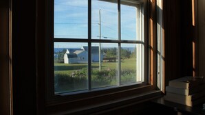A window with a view of a house and a grassy area.