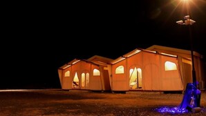 A series of tents illuminated by a single bright light source, with a clear view of their structure and entrance.