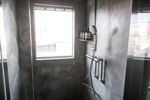 Een douche met een raam, een handdoekhouder en toiletartikelen op een plank.
