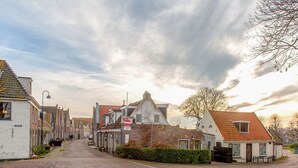 Une rue pavée bordée de bâtiments traditionnels européens, un panneau indiquant l’interdiction de circuler, et un ciel dégagé.