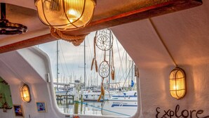 L'intérieur d'un bateau donnant sur une marina, avec des attrape-rêves et le mot « Explore » écrit sur le mur.