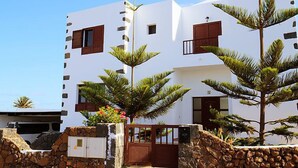 A white building with multiple windows and a stone wall entrance. - Villa Mareta by Interhome (Tinajo)