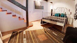 A bedroom with a bed, a staircase, and a wooden floor. - Villa Mareta by Interhome (Tinajo)