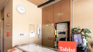 Un comptoir d’accueil avec une horloge, un détecteur d’incendie et une enseigne indiquant « Tabist ».