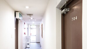 Un couloir d’hôtel avec une porte portant le numéro 704, un comptoir de réception et une porte avec une pancarte dans une langue étrangère.
