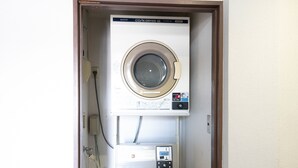 Un appareil compact, comprenant une machine à laver et un sèche-linge, conçu pour être fixé au mur et installé dans un petit espace buanderie.