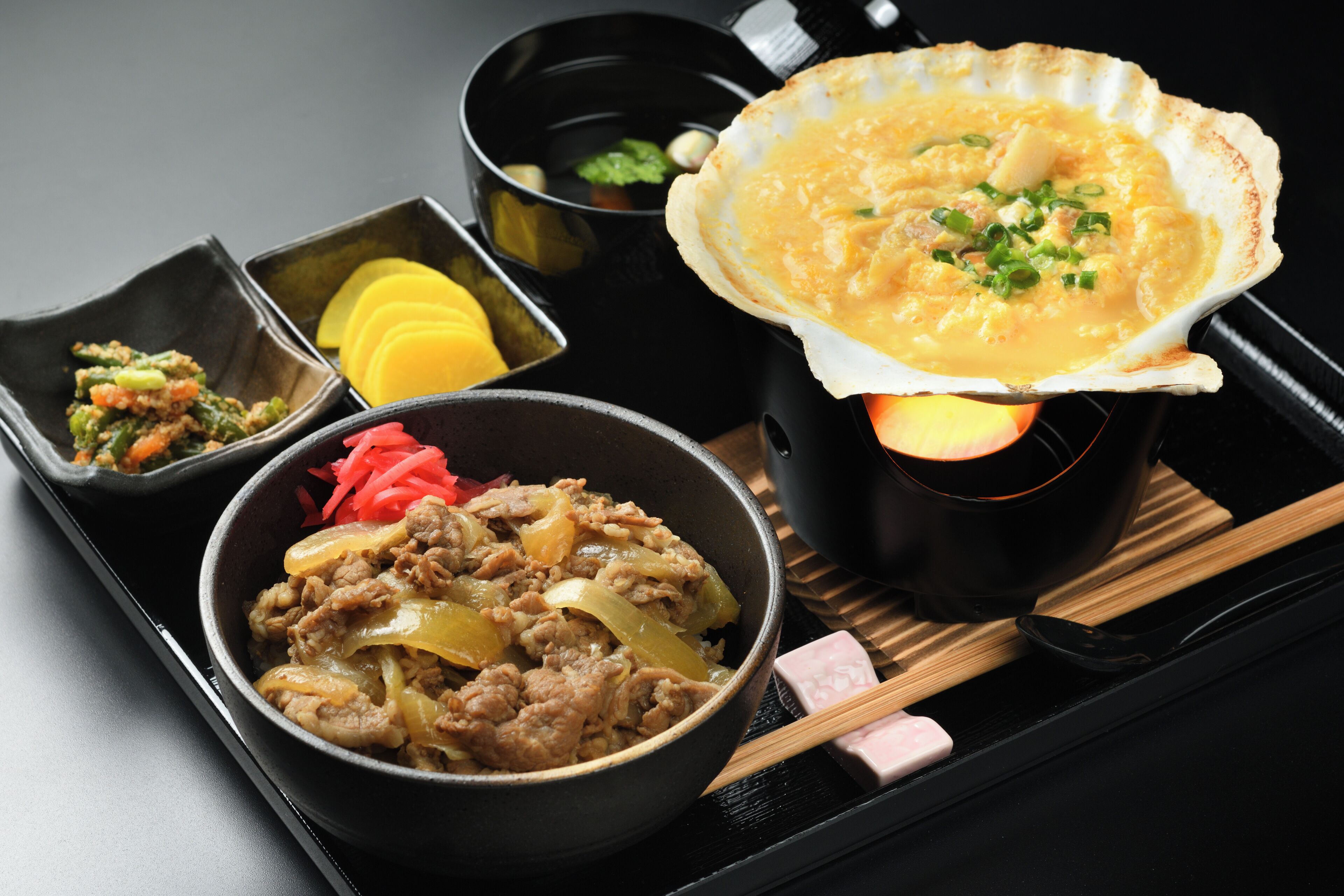 Uma bandeja com diversos pratos, incluindo uma tigela de carne, uma de sopa e uma de legumes.