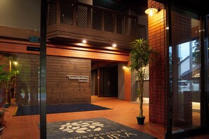 A hotel entrance with a wooden facade, a sign reading "Towadakohan Sakura," and a potted plant in the foreground. - Towadakohan Sakura (Towada)