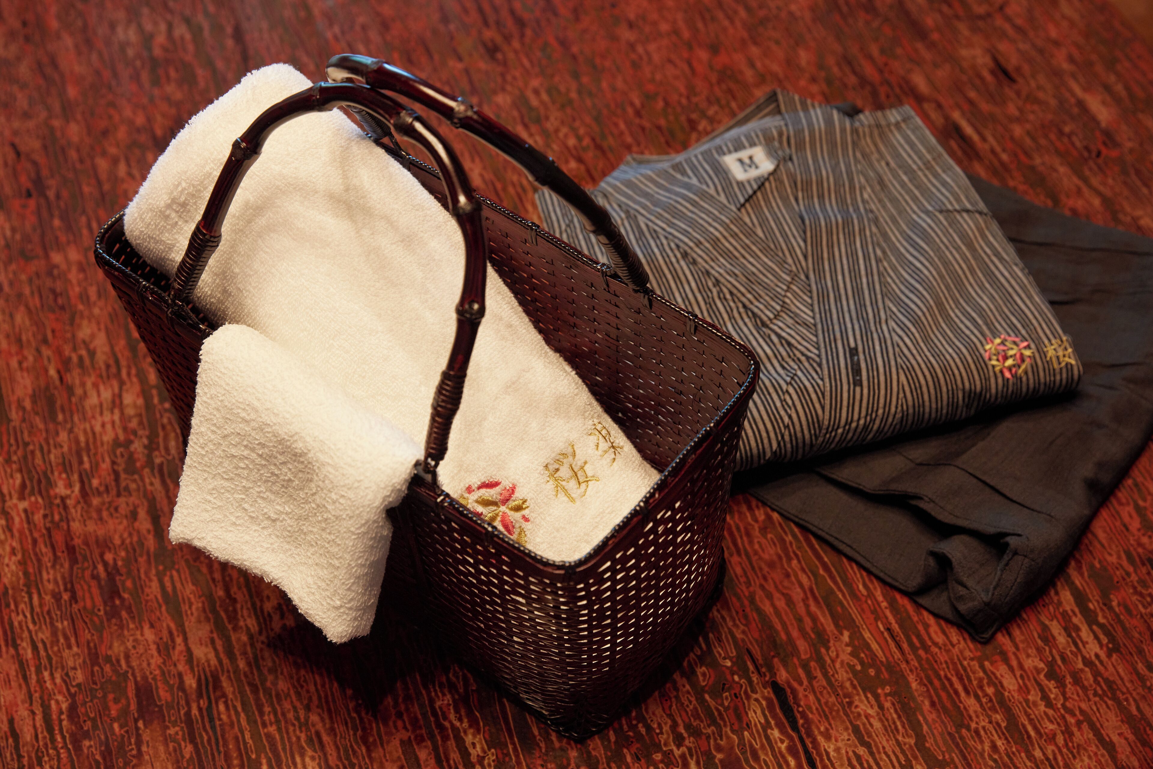 A wicker handbag with a white interior and a folded striped garment with a label.