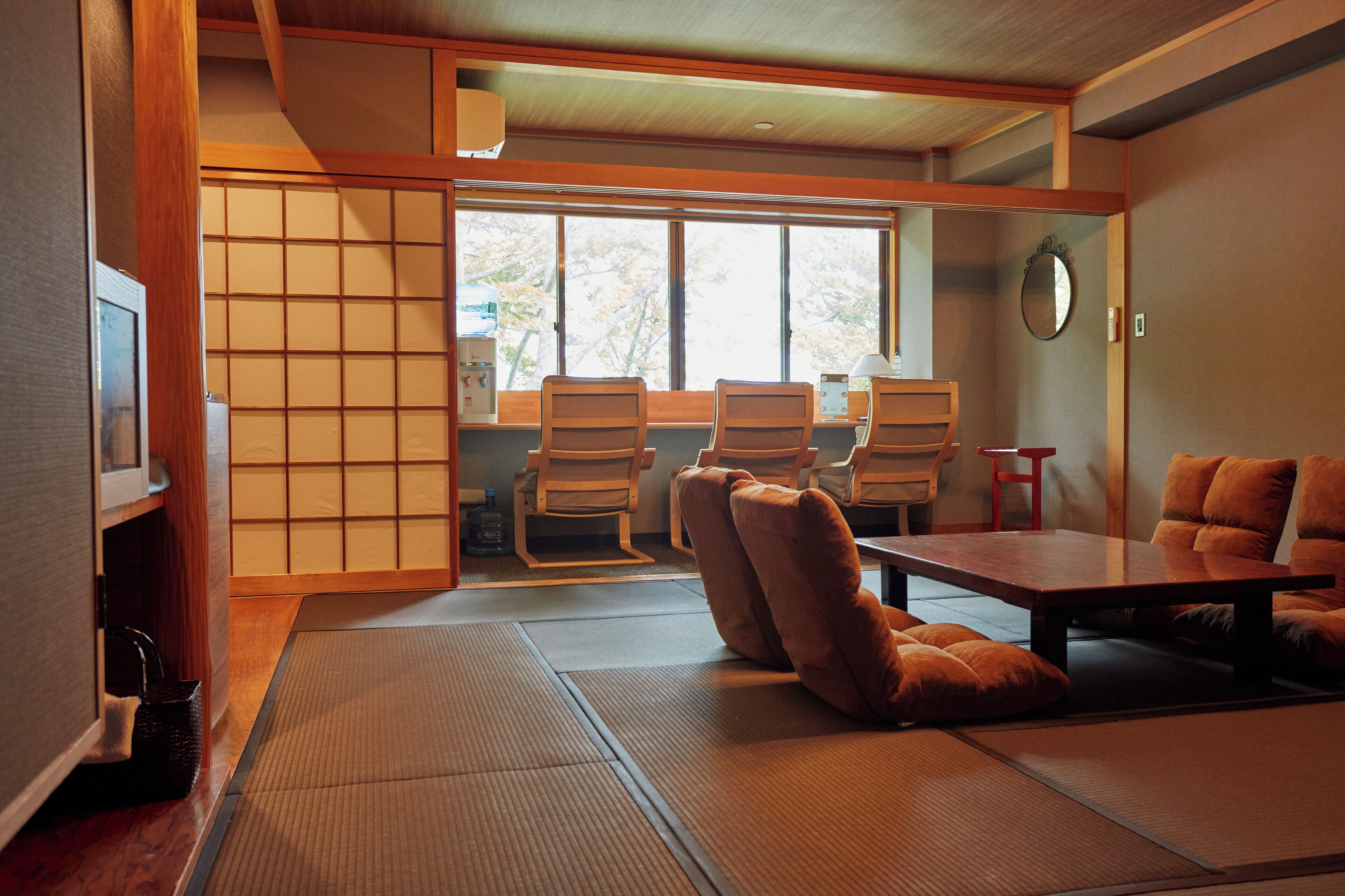 A traditional Japanese room with tatami flooring, a low table, and wooden chairs.