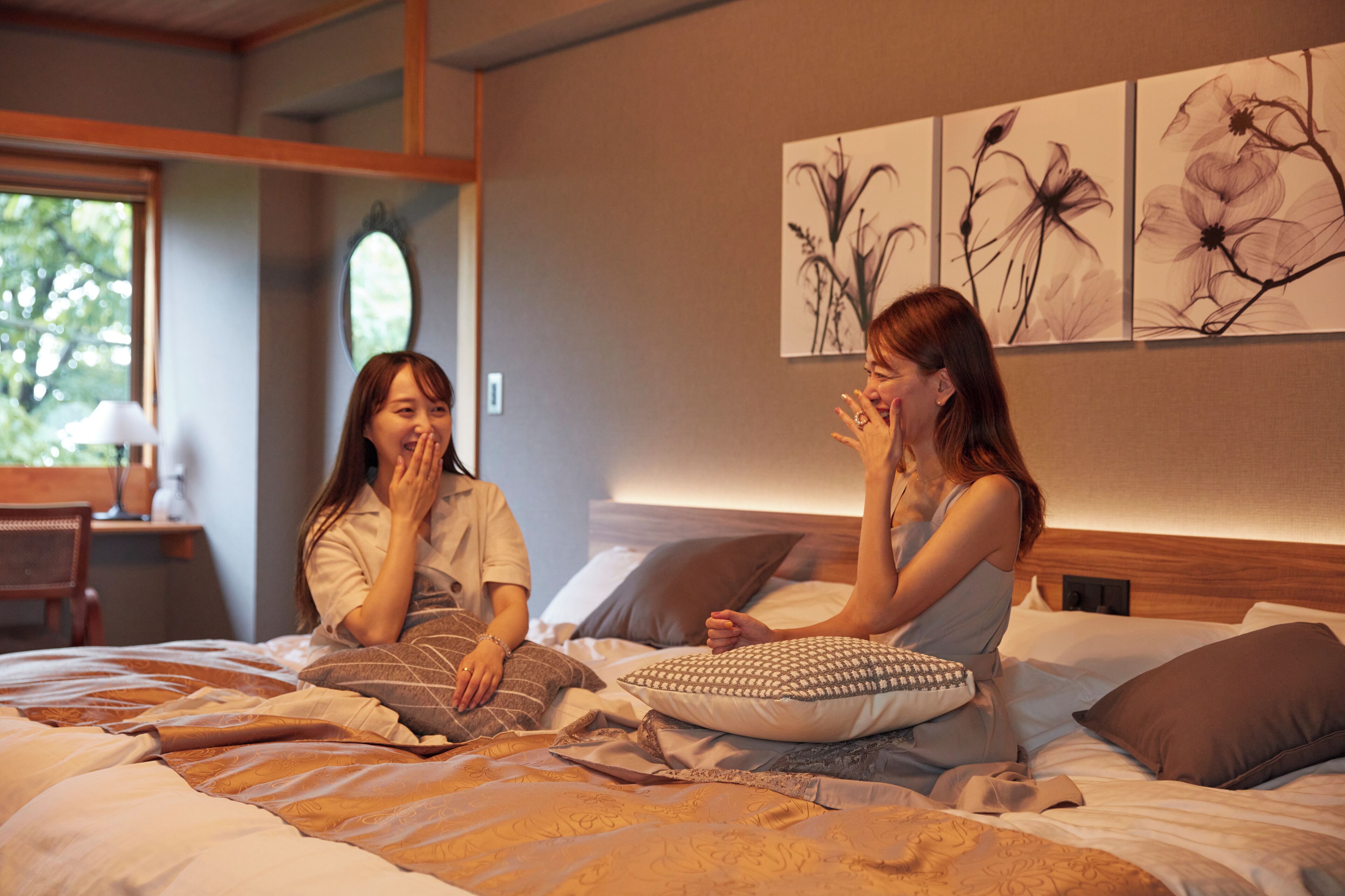 A bedroom with a bed, pillows, and a wall with floral artwork.