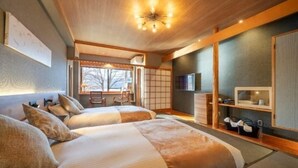 Habitación de hotel con dos camas, televisor, escritorio y vistas al exterior.