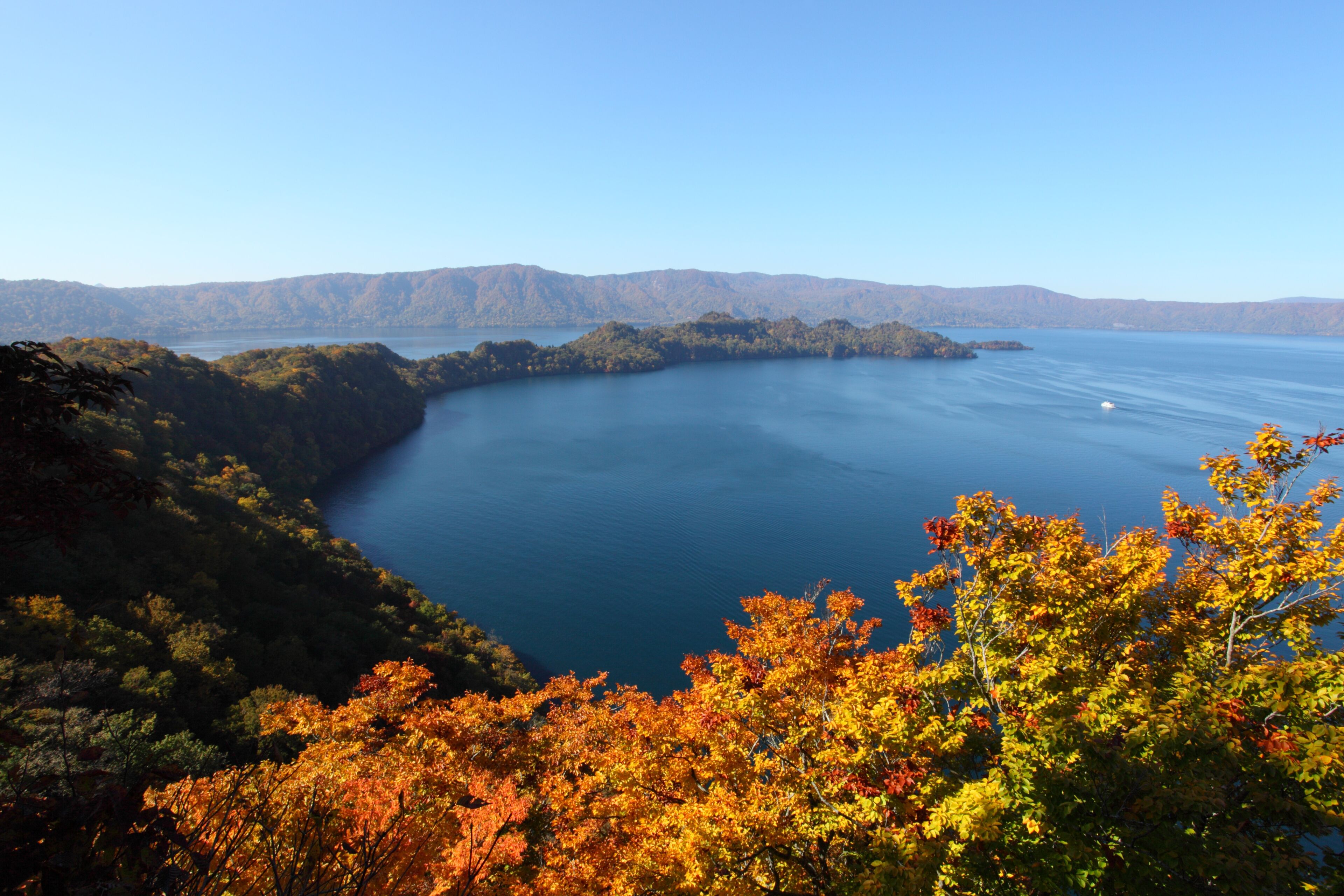 Una vista panorámica de un lago rodeado de colinas boscosas.