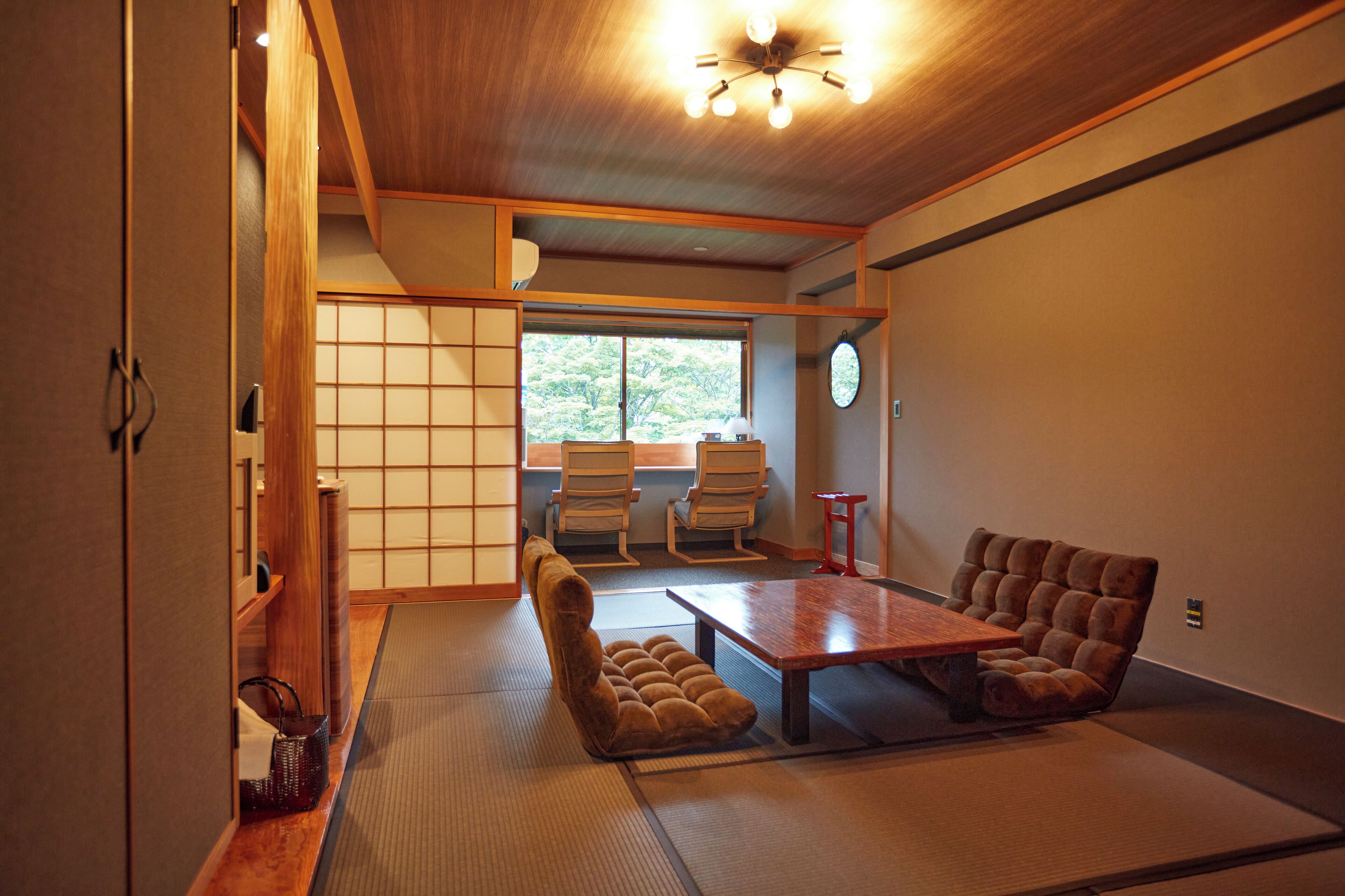 A traditional Japanese room with tatami flooring, a low table, and two cushioned seating areas.