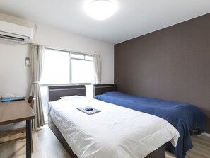 Una habitación de hotel con una cama individual, un escritorio y una ventana con cortinas.
