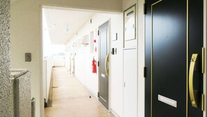 Un pasillo con puertas, un extintor y un termostato en la pared.