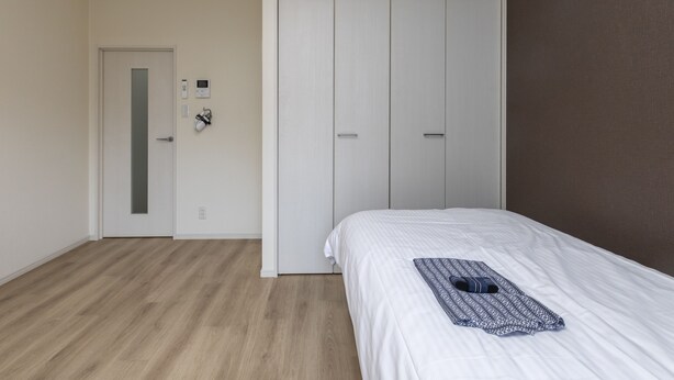 Un dormitorio con cama, armario y puerta con panel de control.