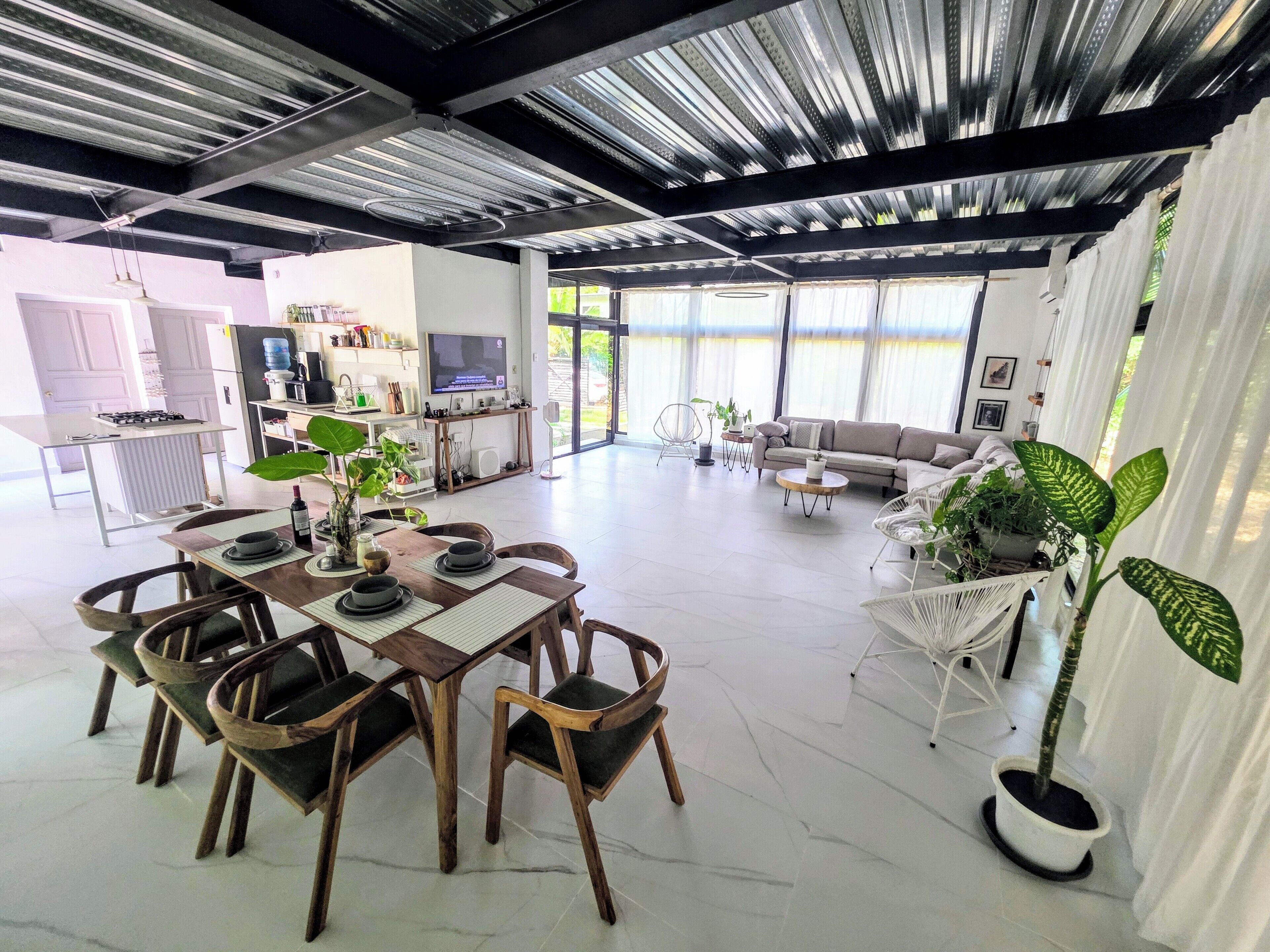 A spacious living area with a dining table, chairs, a sofa, and a TV.