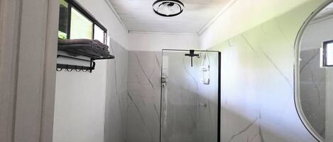 A bathroom with a glass shower enclosure, a toilet, and a sink.