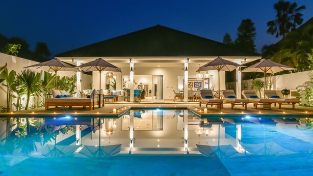 Una casa moderna con piscina, area salotto esterna e patio ben illuminato.