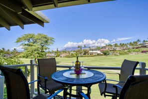 Relax in this serene outdoor seating area with a round table and four chairs, overlooking a well-manicured lawn and golf course.