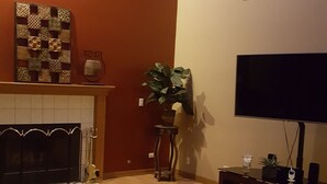 A living room with a fireplace, a large TV, and a sofa. - Winding Meadows Home Away from Home (Bolingbrook)