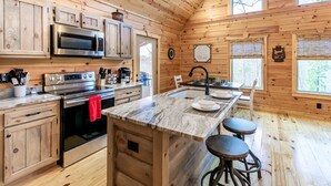 A wooden cabin kitchen with built-in appliances, a central island, and bar stools.