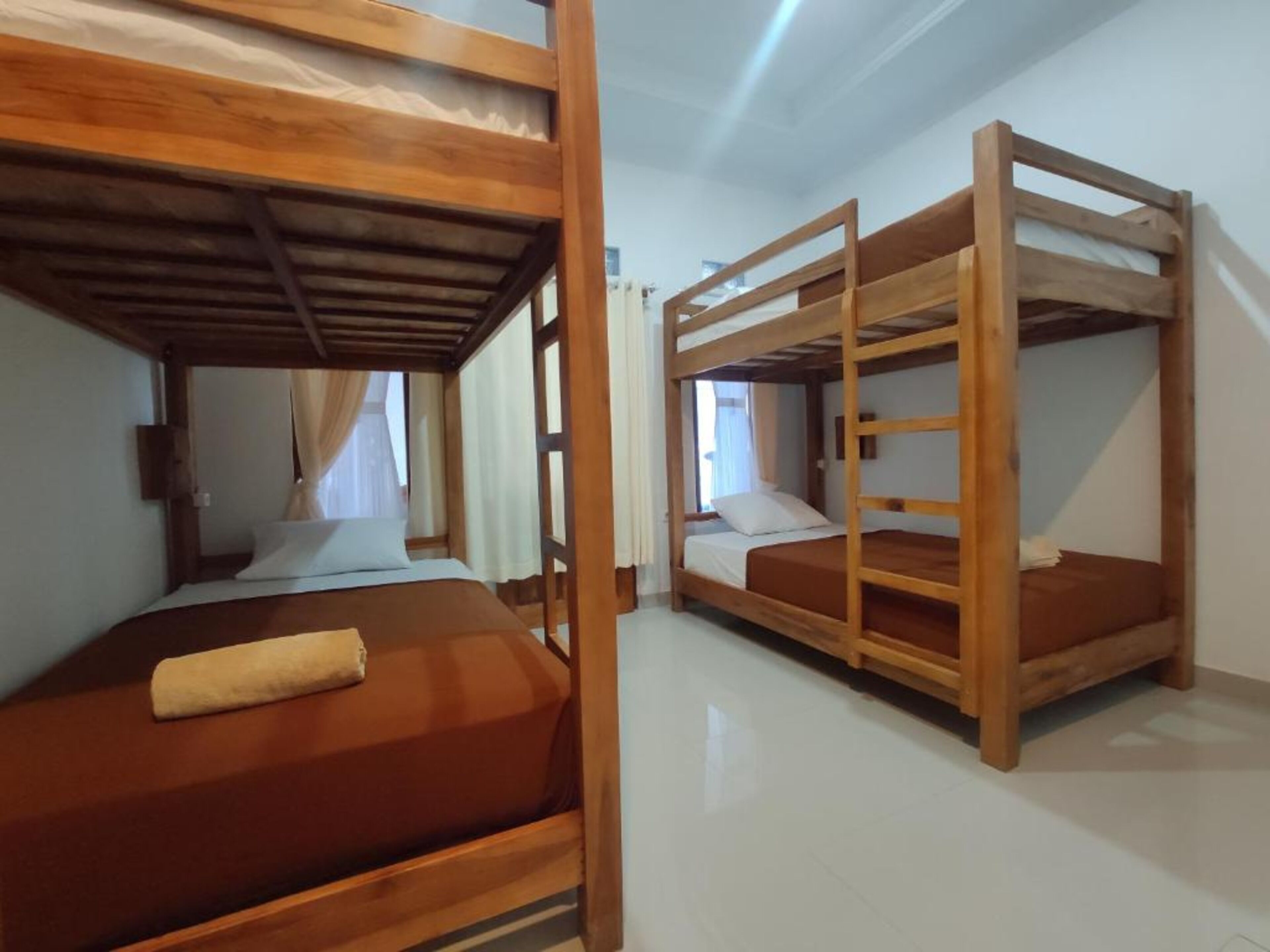 Una habitación con literas, una ventana con cortinas y una cama con una toalla.